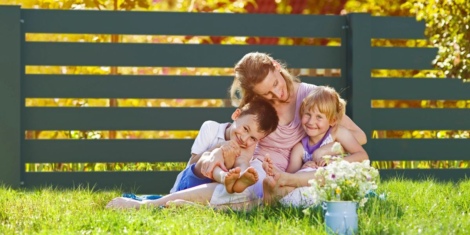 Mutter mit Kindern vor Zaun