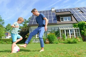 Vater mit Sohn vor Haus mit Solaranlage